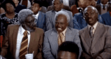 Three men in suits and ties are sitting in a crowd10884184573523275770